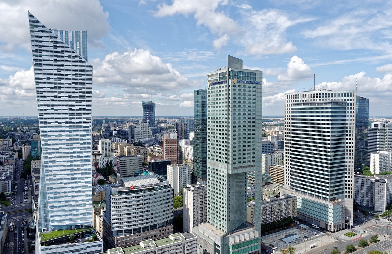 A cityscape dominated by tall commercial buildings against a partly cloudy sky, representing the significant footprint and visual impact of office spaces in a large city.