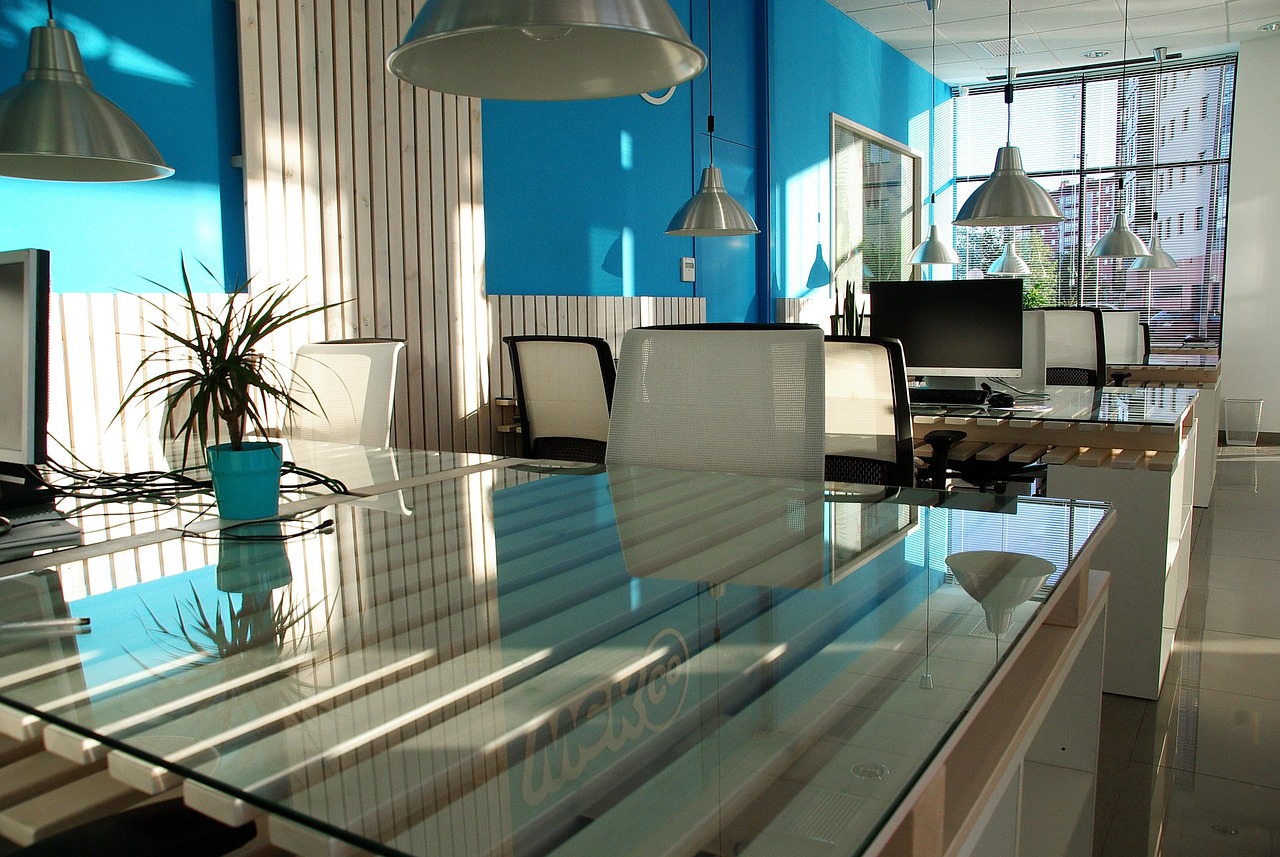 Commercial office space with an open layout, glass desks, and modern design elements.