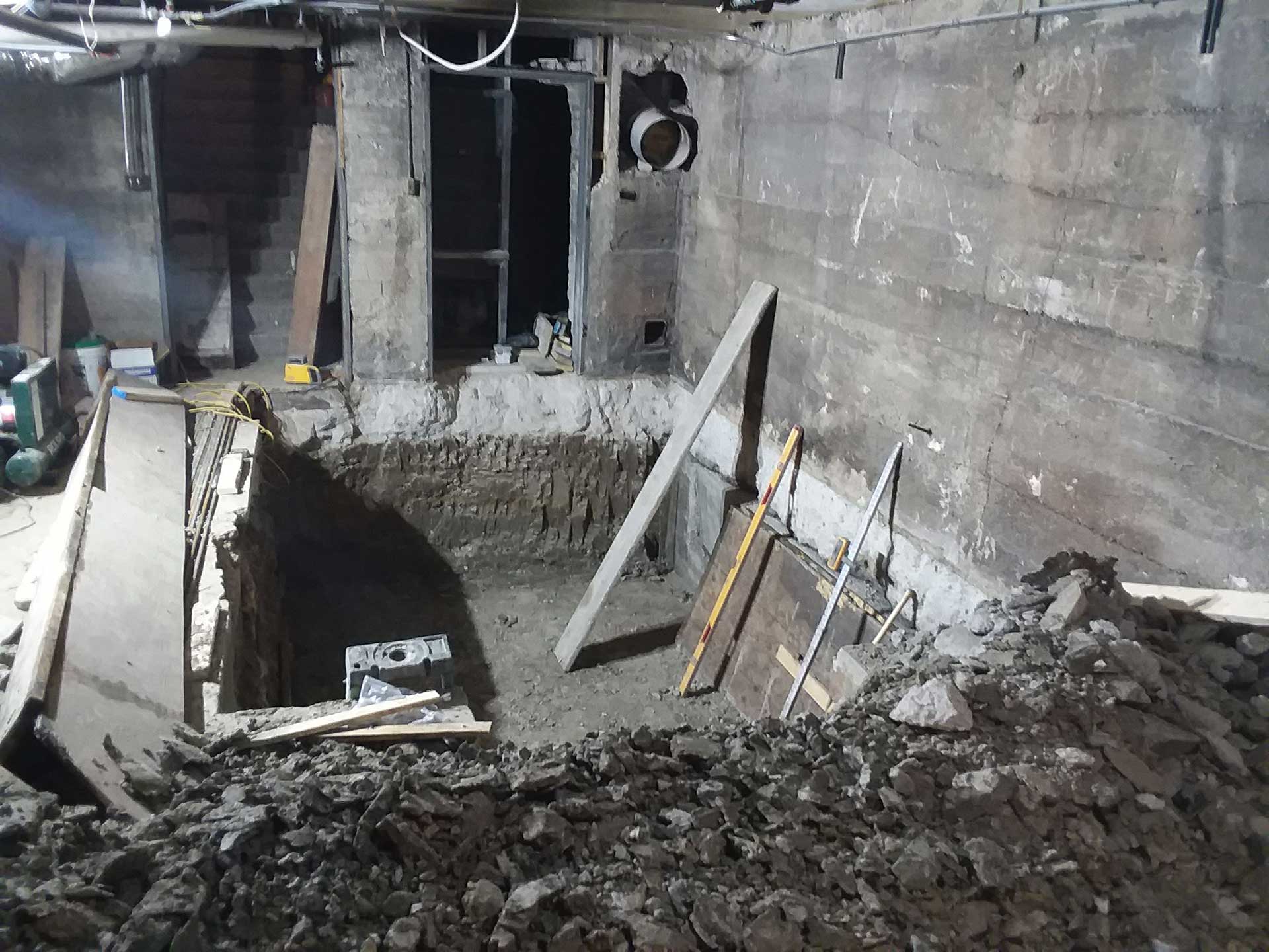 An image of an elevator shaft under construction with construction materials around the open pit.